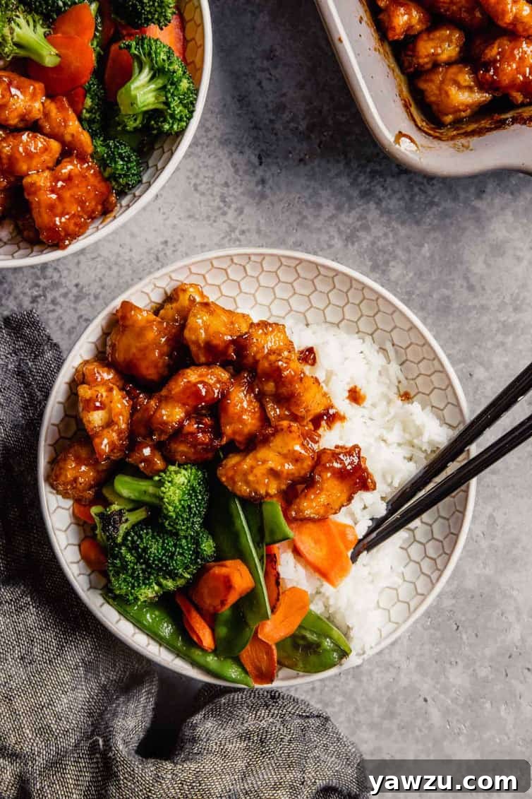 A vibrant display of freshly prepared sweet and sour chicken and stir-fry vegetables in a white bowl, with chopsticks, set against a modern gray counter, and more portions visible in the background.