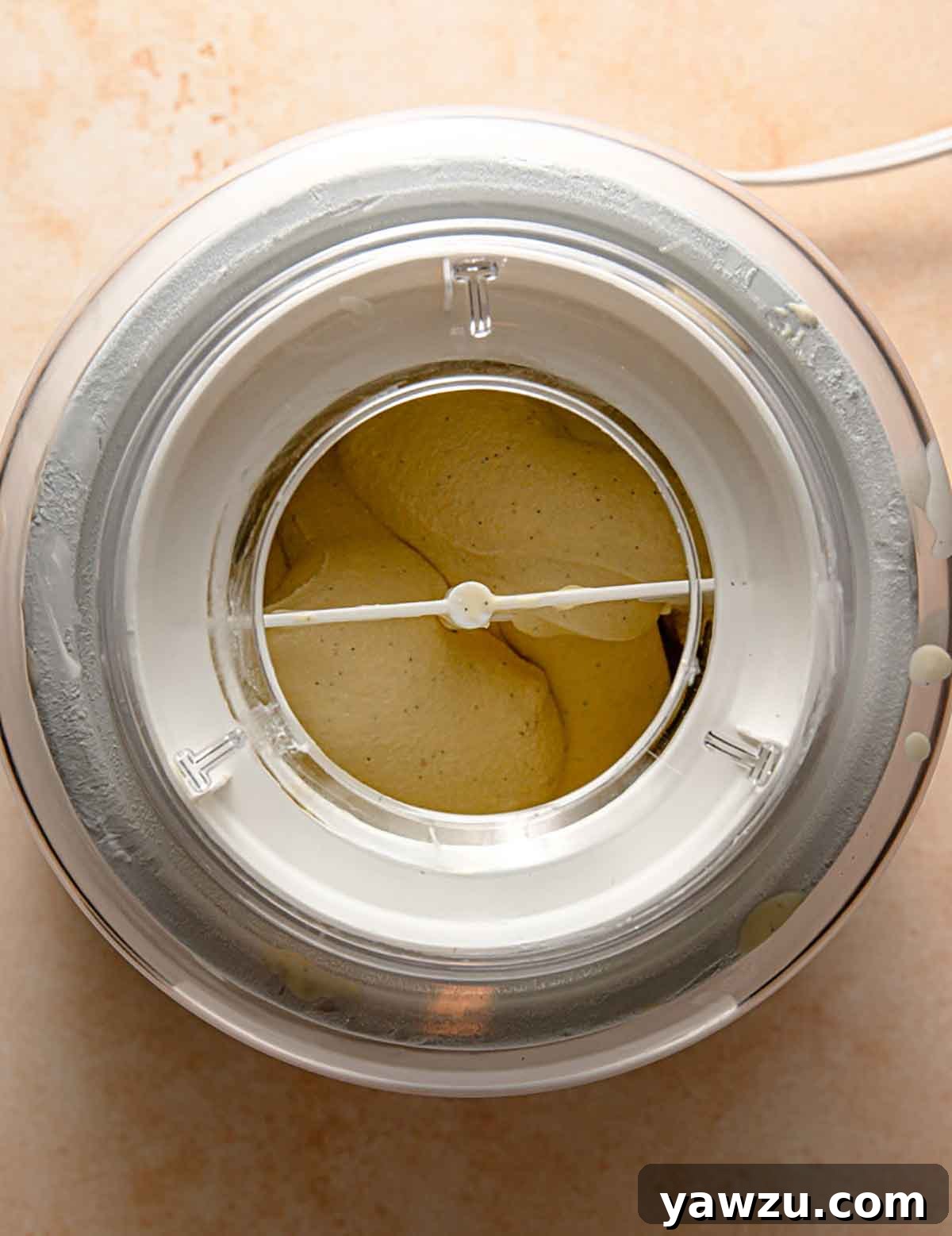 Overhead photo of vanilla ice cream churning in an ice cream maker.