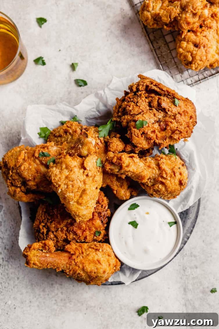 A pan of crispy buttermilk fried chicken with a small ranch dipping cup.
