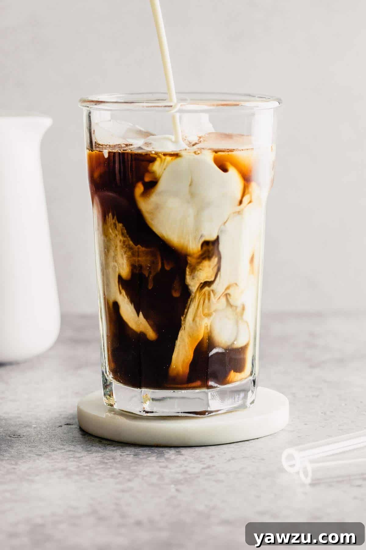 A frosty glass of delicious iced coffee with a straw, perfect for a refreshing start to the day.