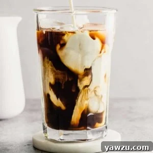 A glass of iced coffee with milk before stirring on a coaster.