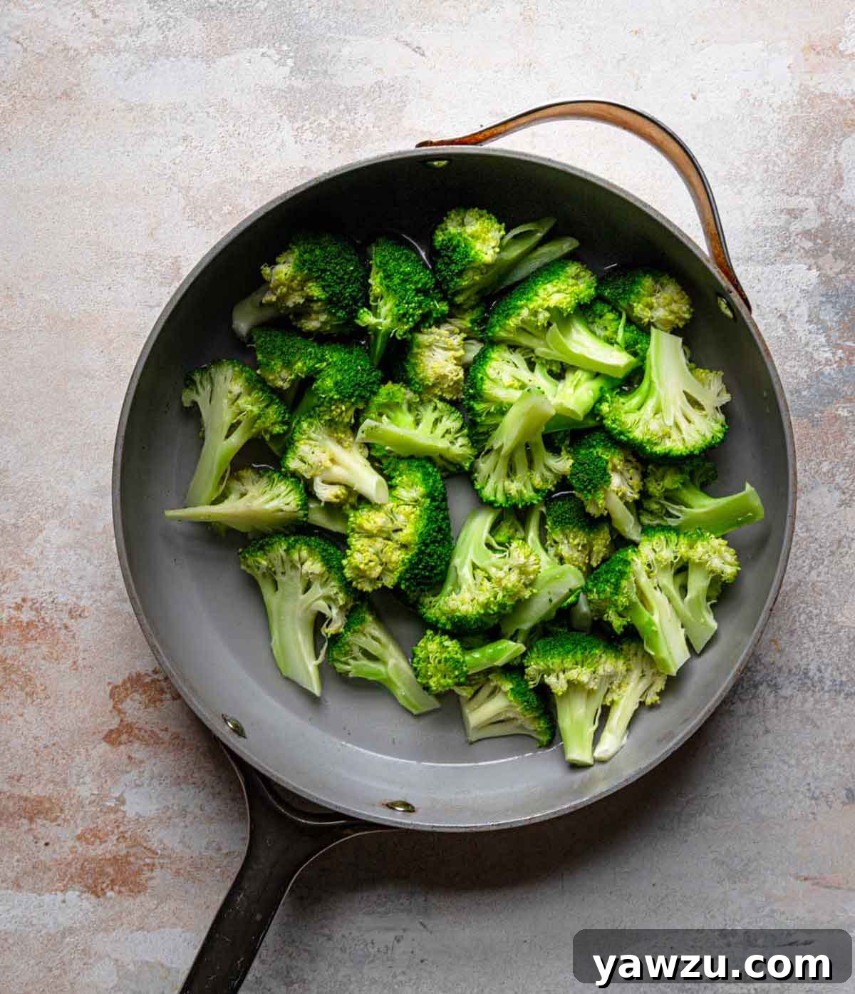 Overhead photo of pan with vibrant green broccoli florets being steamed.