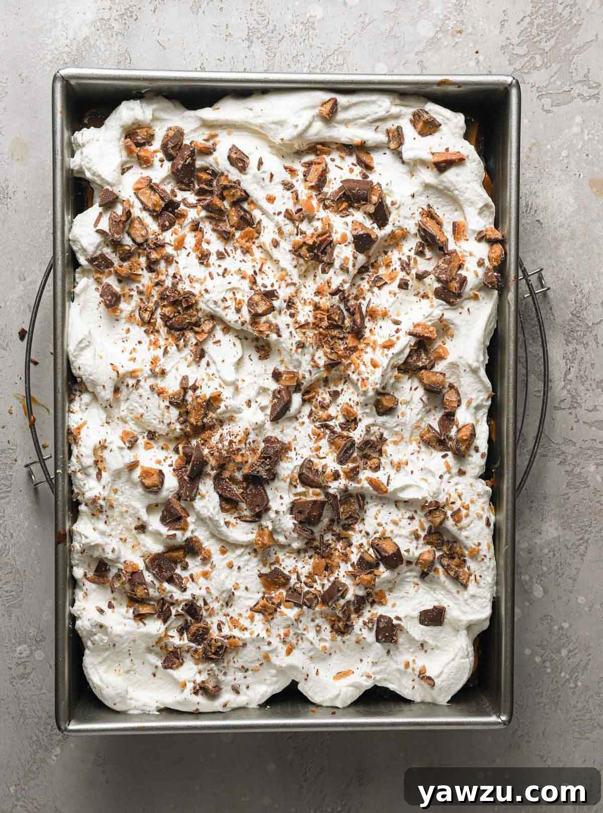 Overhead photo of assembled better than sex cake topped with whipped cream and crushed Heath bars, ready to be served.