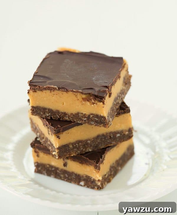Delicious Peanut Butter Nanaimo Bars stacked on a plate, showcasing the chocolate, peanut butter, and ganache layers