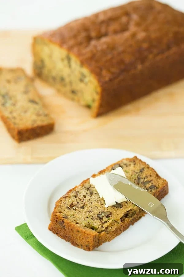 A generous slice of incredibly moist Zucchini-Banana Bread, highlighting its tender crumb and nutty additions