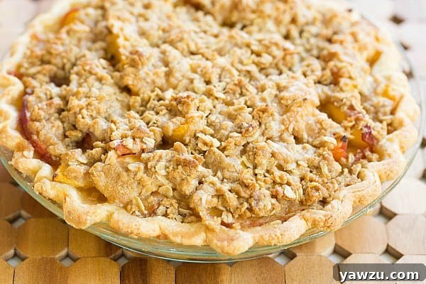 Juicy Peach Crumble Pie with a golden, crisp topping, perfect for summer dessert.