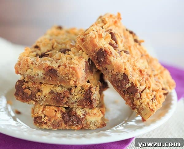 Close-up of a single perfectly cut Seven Layer Bar, revealing the distinct layers and chewy texture ready for a bite.