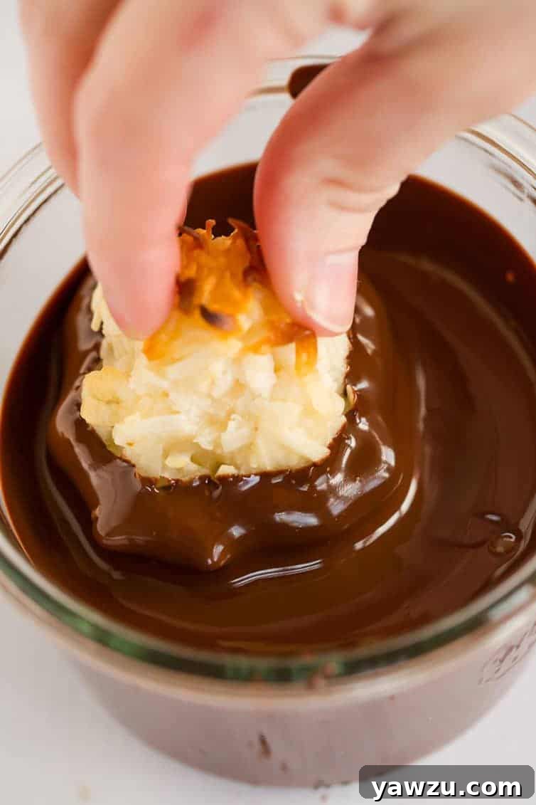 Perfectly baked coconut macaroons waiting to be dipped in chocolate, arranged on a baking sheet.