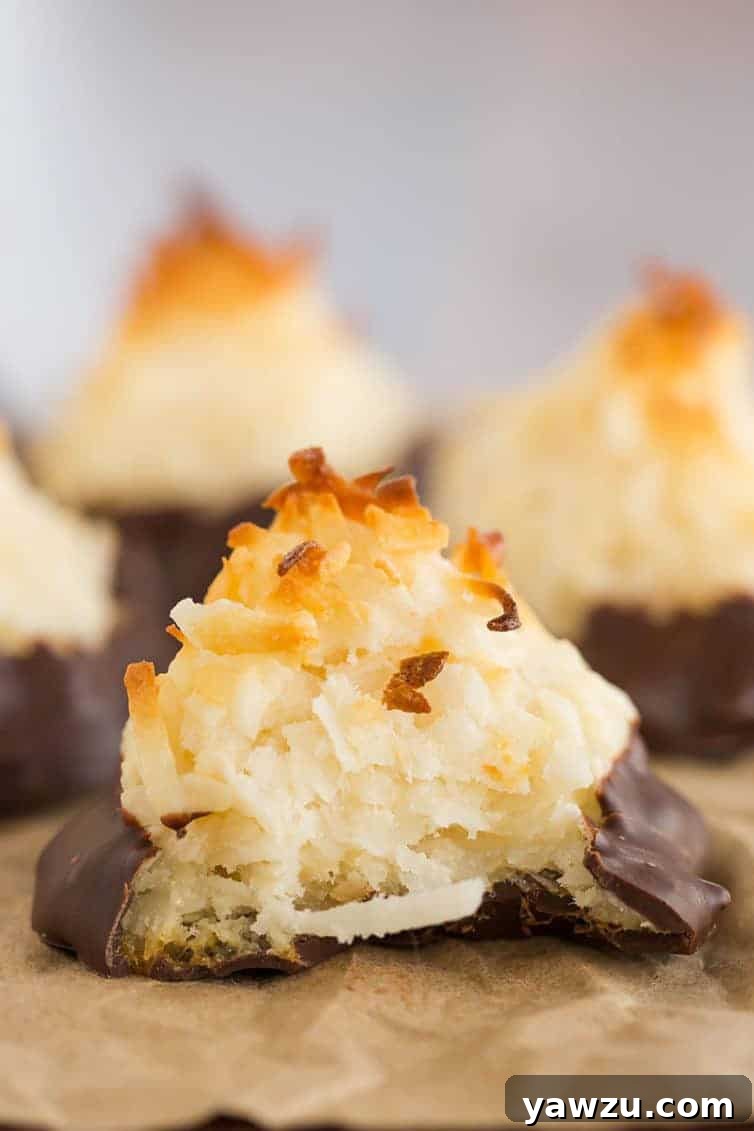 Stack of chocolate-dipped coconut macaroons on a white plate, elegantly presented and ready to be served.