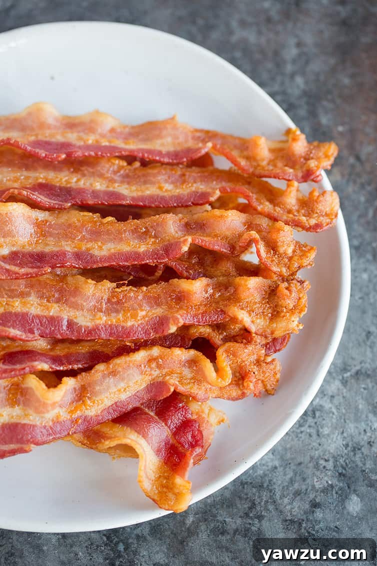 A plate with slices of oven baked bacon, perfectly crispy and golden brown.