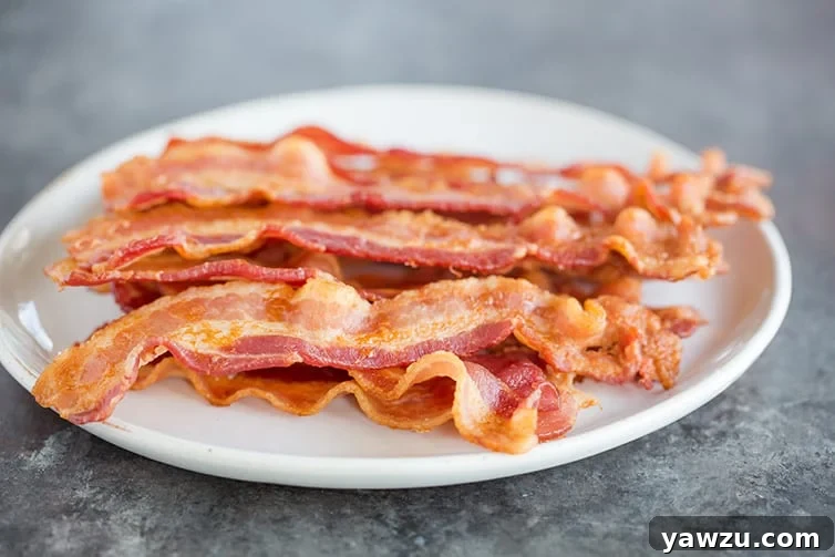 A close-up of a perfectly cooked plate of bacon, demonstrating its irresistible crispness and golden hue.