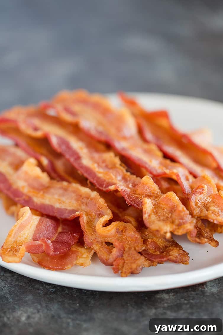A generous plate piled high with golden, crispy oven baked bacon, ready to be enjoyed.