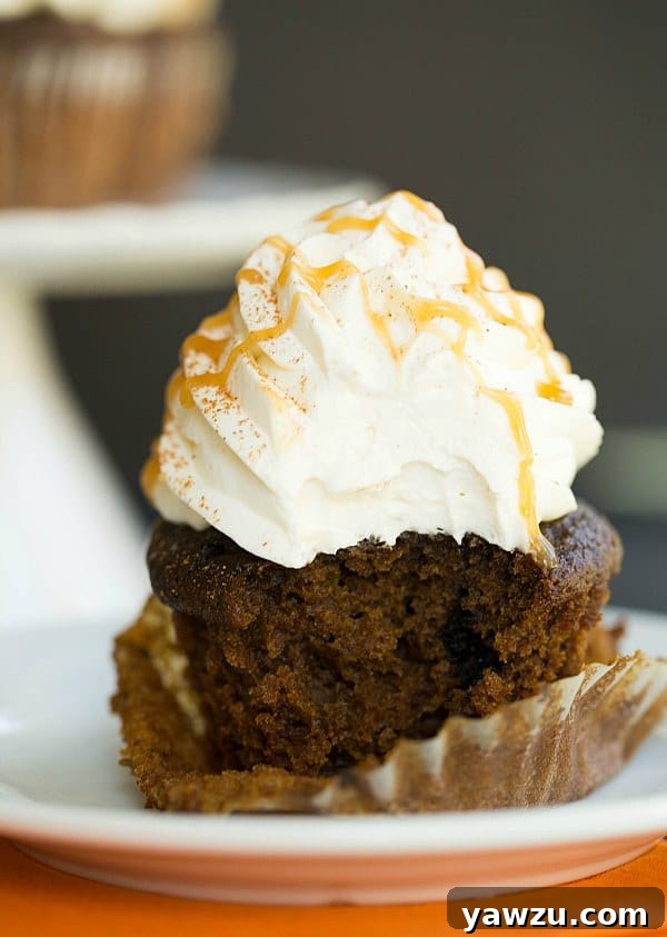 Enjoying a bite of a Pumpkin Spice Latte Cupcake, showing off the fluffy frosting.
