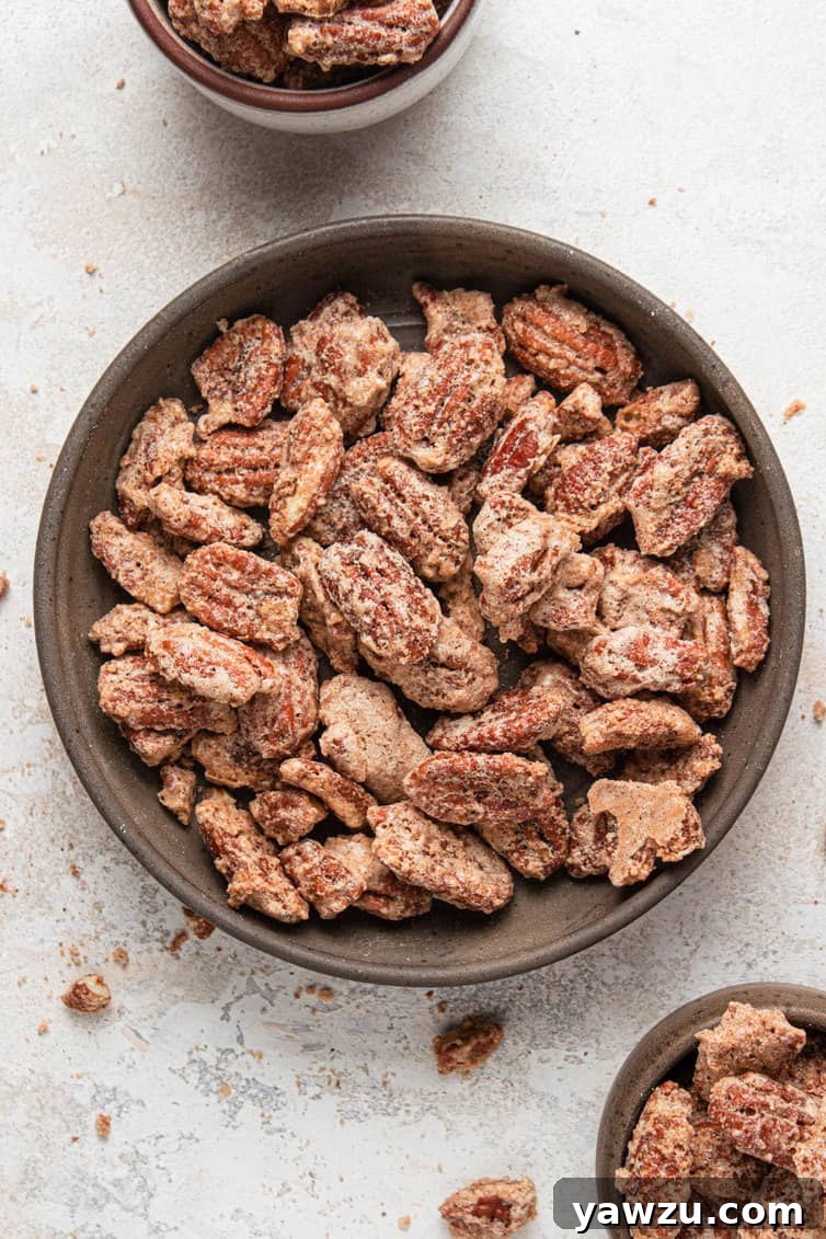 A brown bowl with candied pecans on a white counter with small bowls of candied pecans.