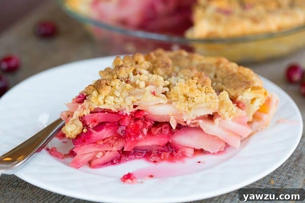 A whole Cranberry-Ginger Pear Pie, freshly baked with a golden crumble topping, cooling on a wire rack.