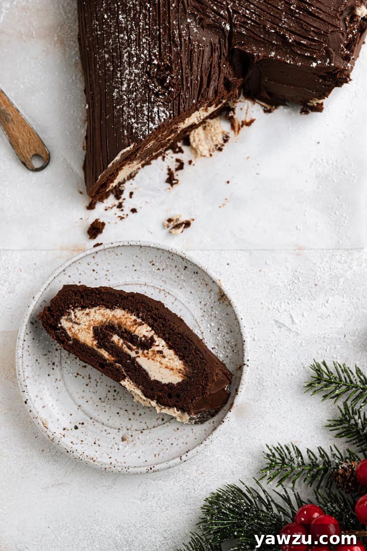 A slice of Buche de Noel (Yule Log) on a white plate.