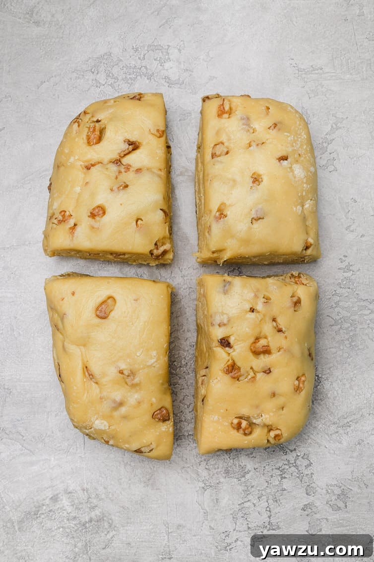 Biscotti dough, skillfully divided into four equal pieces on a countertop, ready for shaping into logs.