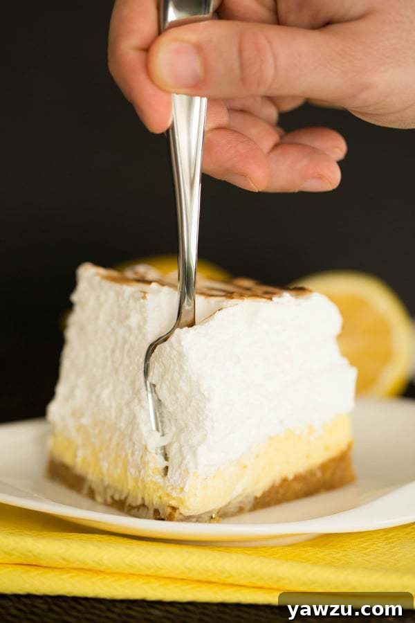 Close-up of a single slice of Sky-High Lemon Meringue Bar, showing the distinct layers.