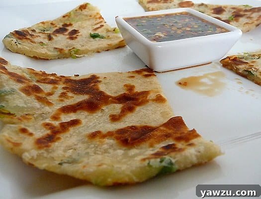 Scallion pancakes with a ginger dipping sauce on a white plate.
