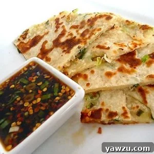 Scallion pancakes with a ginger dipping sauce on a white plate.