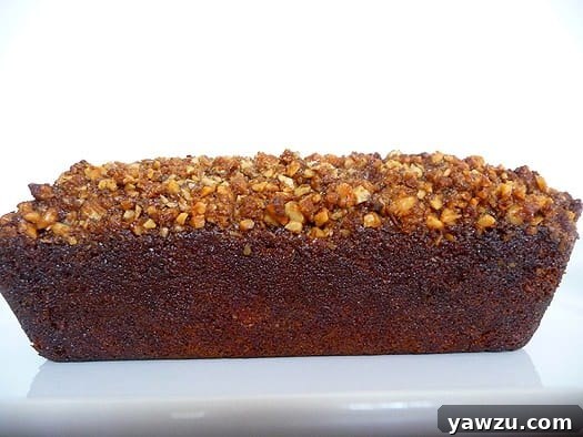 A freshly baked loaf of Bananas Foster Banana Bread resting on a white plate, showcasing its golden-brown crust and inviting texture.