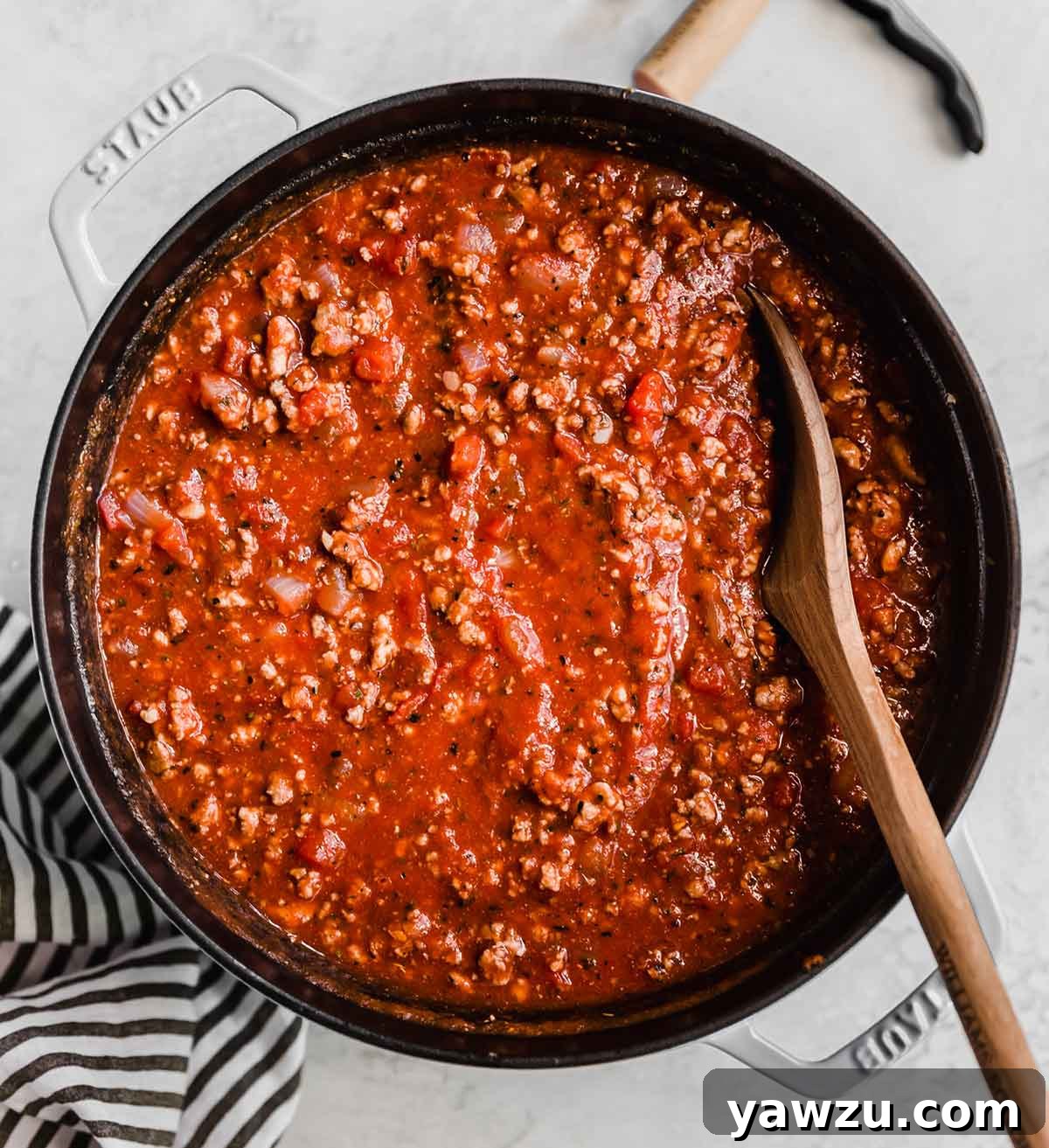 Overhead photo of a pot of meat sauce with a wooden spoon in the pot.
