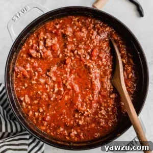 A bowl of homemade meat sauce with a wooden spoon.