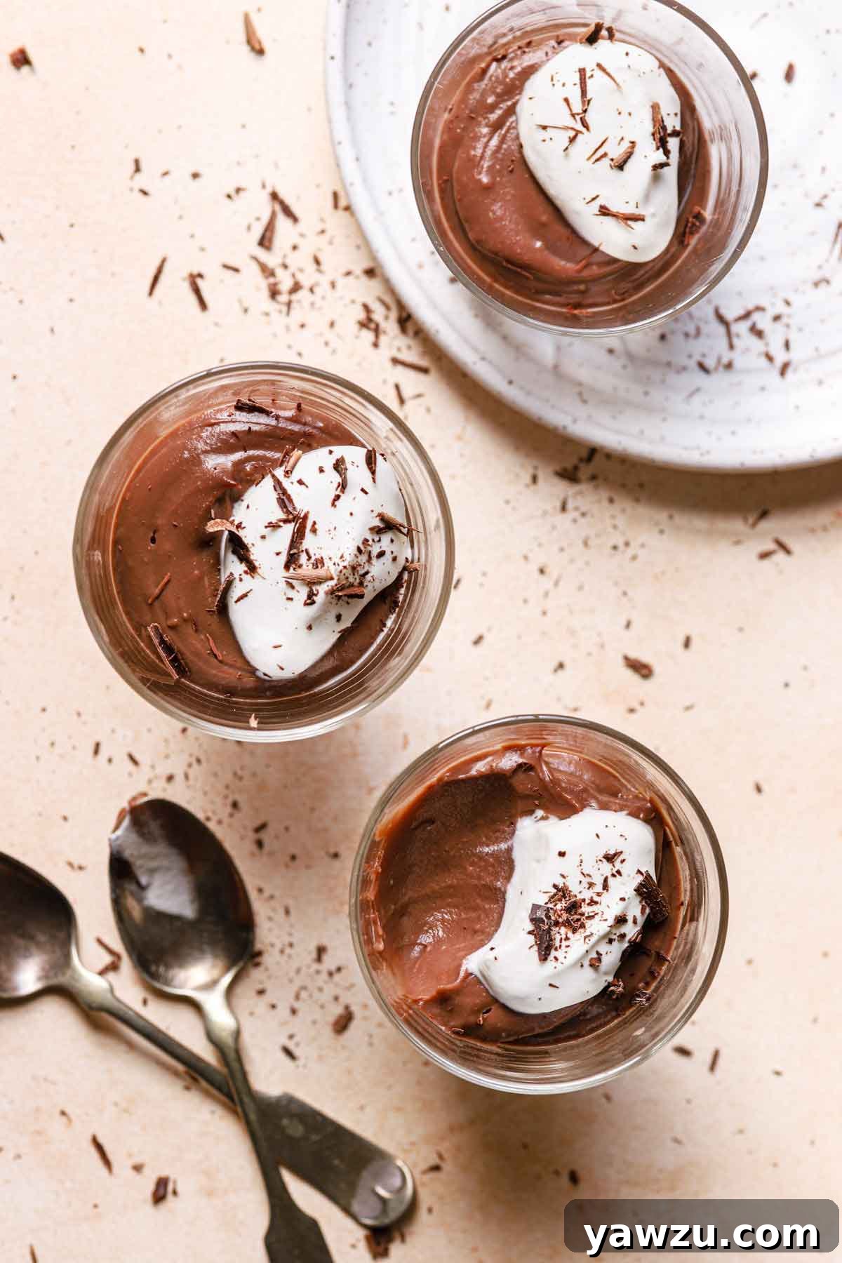Overhead photo of three glass cups filled with chocolate pudding and a spoonful taken out of one.