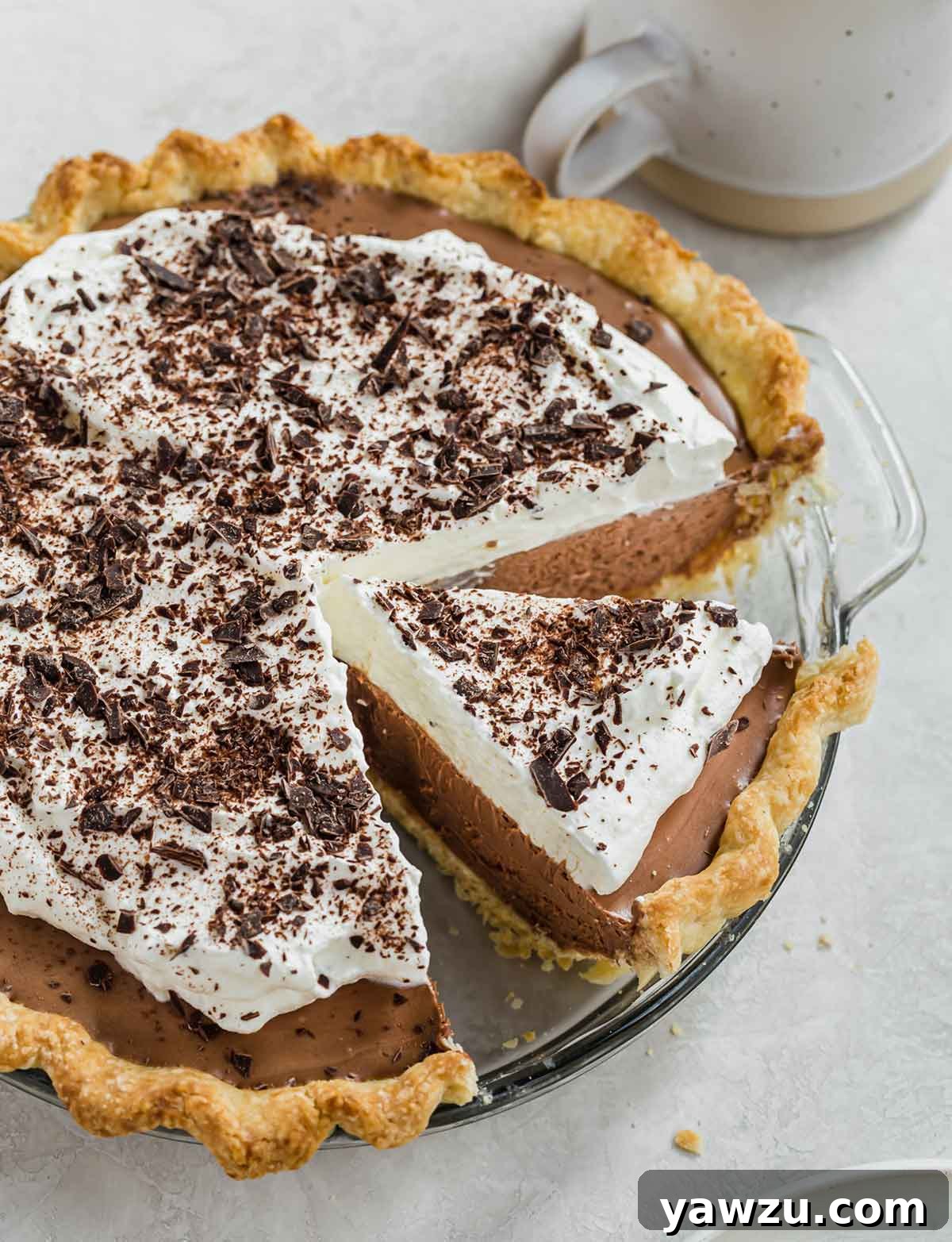 Overhead photo of French silk pie in glass pie plate with one slice cut away from rest of pie but still in the plate.