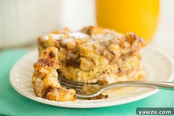 A serving of Cinnamon Roll Bread Pudding on a plate, garnished with fresh berries and a generous drizzle of maple syrup, ready to be enjoyed.