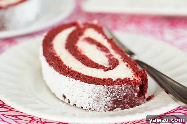 Slice of Red Velvet Roll Cake, showing the intricate swirl and rich filling.