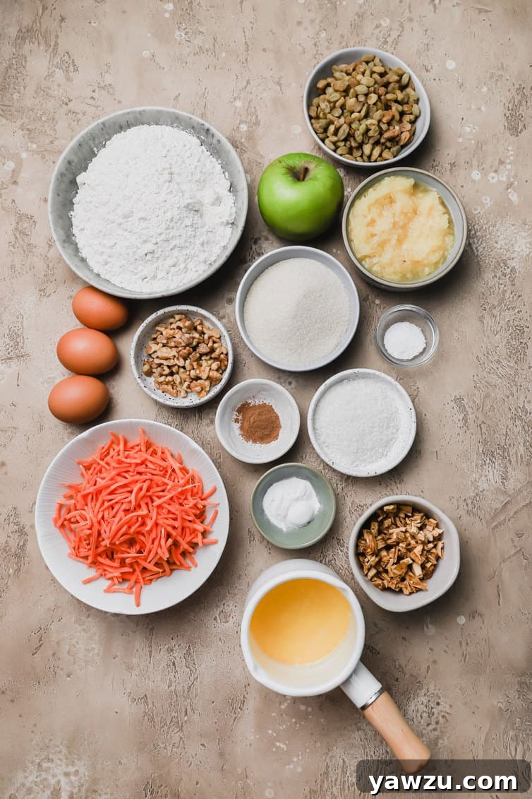 Assortment of fresh ingredients for Morning Glory Muffins prepped in bowls on a kitchen counter, including shredded carrots, apples, pineapple, and various spices, ready for baking.