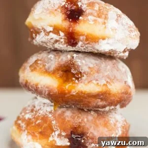 A stack of three paczki with fruit filling.