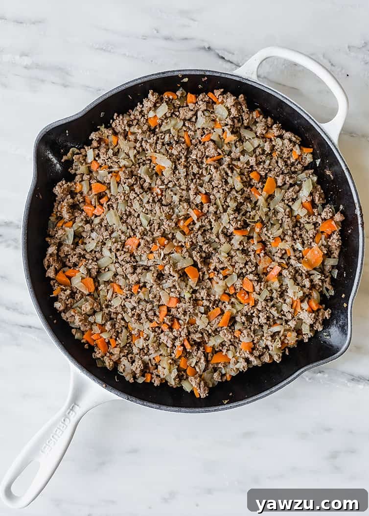 A skillet filled with the rich, cooked meat and vegetable mixture that forms the flavorful base of Shepherd's Pie.