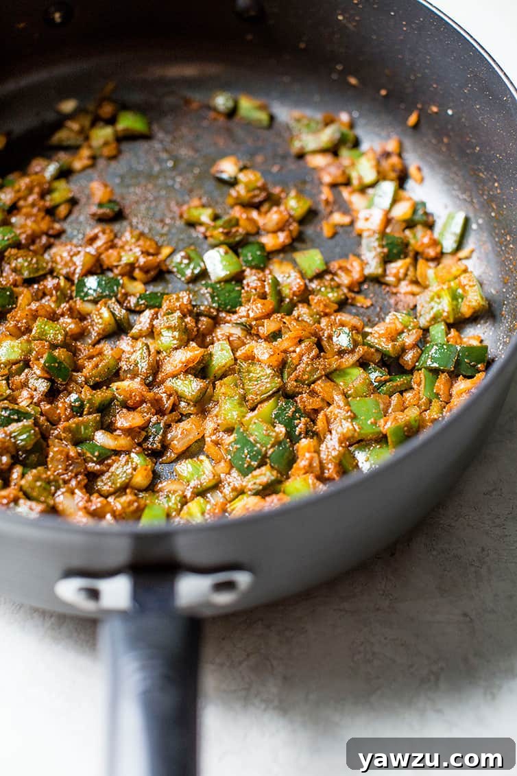 Onion, peppers and seasonings sauteed in a pot.