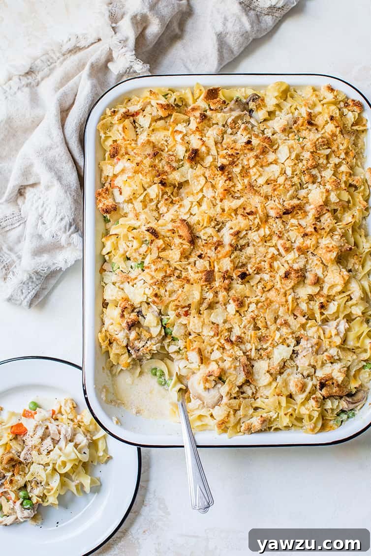 A beautifully baked dish of homemade tuna noodle casserole, with a serving perfectly scooped onto a plate, ready to be enjoyed.