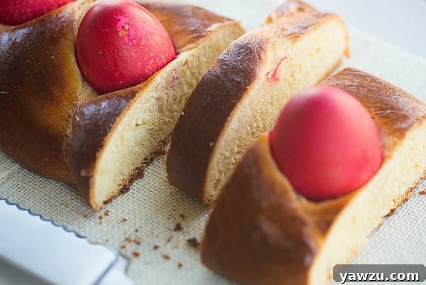 Greek Easter Bread [Tsoureki] - A close-up of the perfectly baked, golden-brown crust of Greek Easter Bread with a glimpse of the red egg.