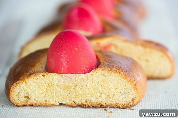 Greek Easter Bread [Tsoureki] - A beautifully arranged full loaf of Greek Easter Bread, sliced, showing the soft interior and the decorative red eggs.