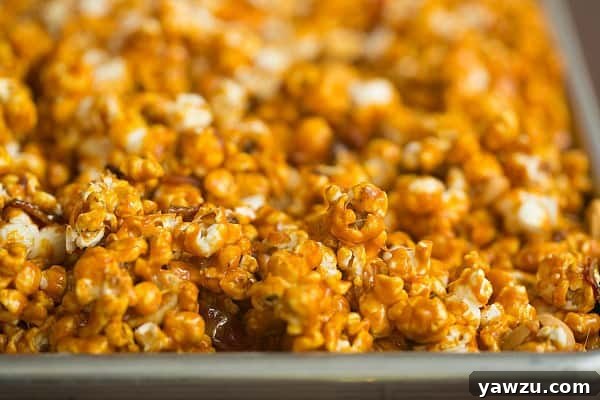 Bourbon Bacon Cashew Caramel Corn spread evenly on a baking sheet, ready to cool and break apart.
