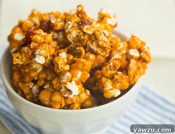 Hand reaching for a piece of the gourmet Bourbon Bacon Cashew Caramel Corn, highlighting its enticing appeal.