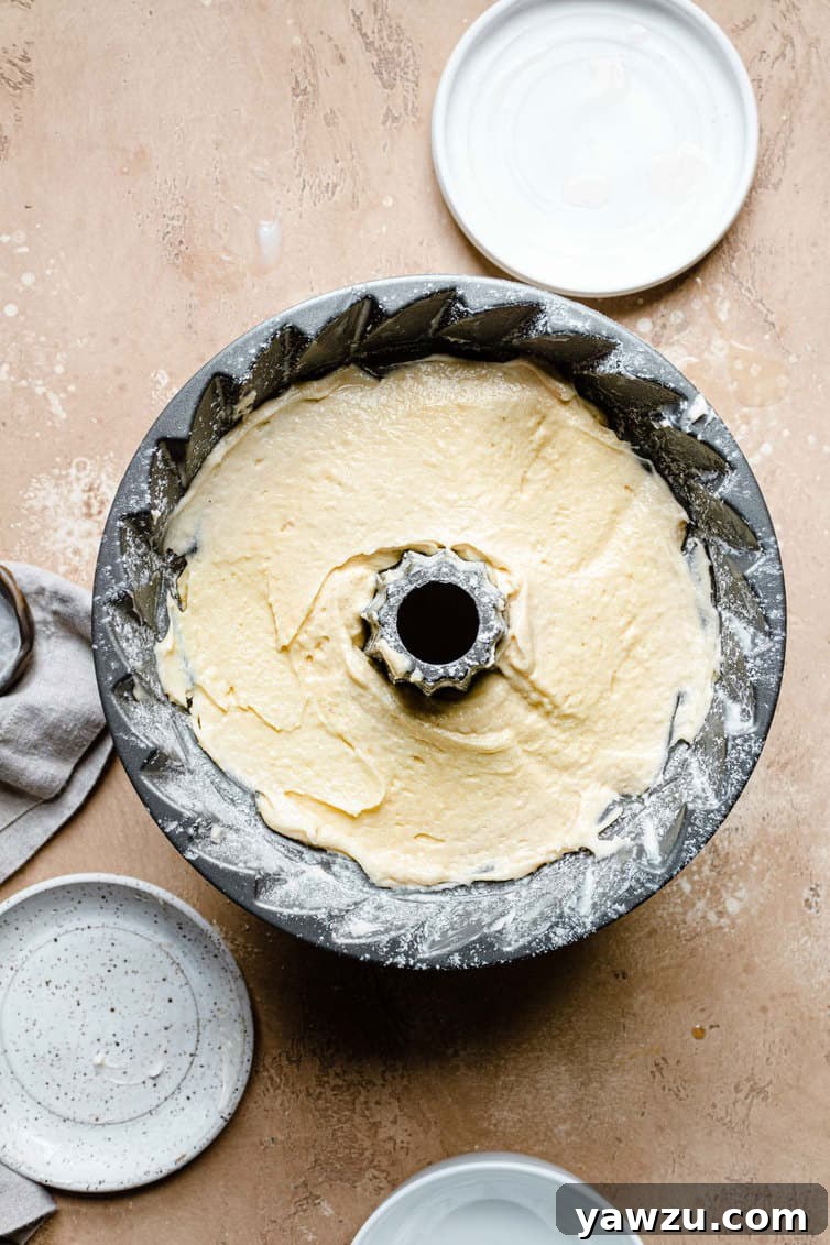 Butter cake batter filling a classic Bundt pan before baking.