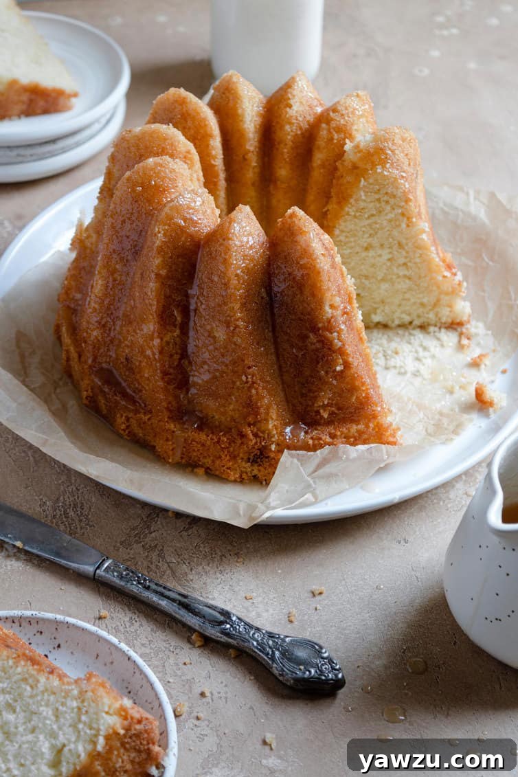 A freshly baked Bundt-style butter cake on a serving platter, with one slice removed to show its interior.