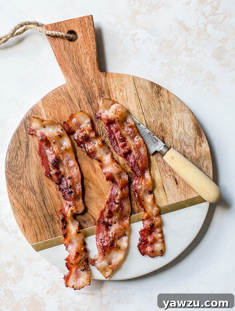 Three slices of bacon on a cutting board.
