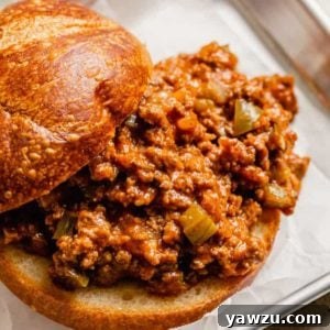A square photo from the front of a sloppy joe sandwich with the top of the bun slid back to show the sloppy joe meat.