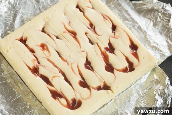 Close-up of a Strawberry Swirl Cheesecake Bar showing the vibrant red strawberry jam swirled into the creamy cheesecake layer.