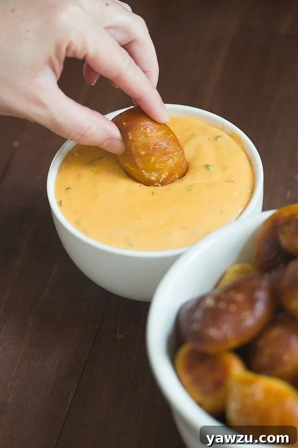 A wide view of a platter filled with soft pretzel nuggets and a small bowl of spicy cheese sauce, ready for a gathering.