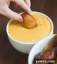 A serving of homemade soft pretzel nuggets with a side of spicy cheese dipping sauce.