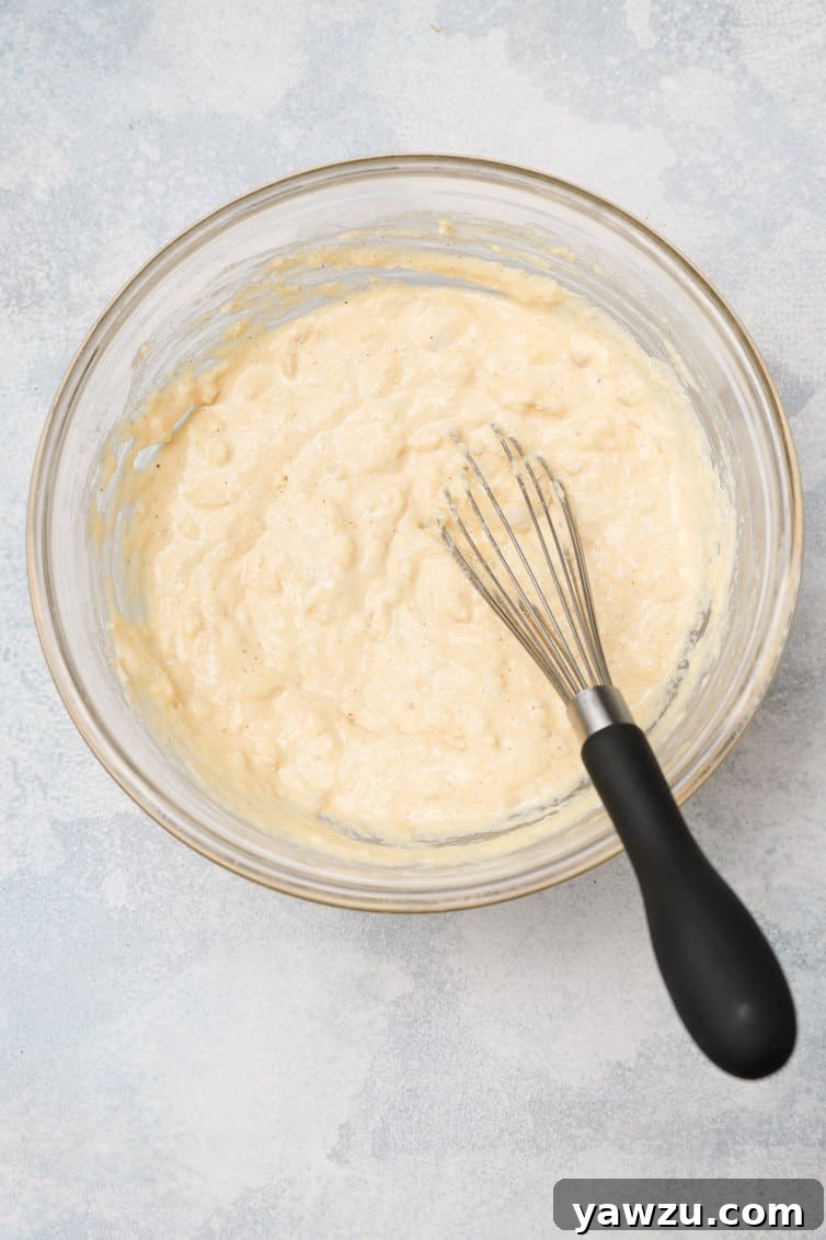 A bowl of freshly mixed hush puppy batter, with a whisk resting in it, ready for frying.