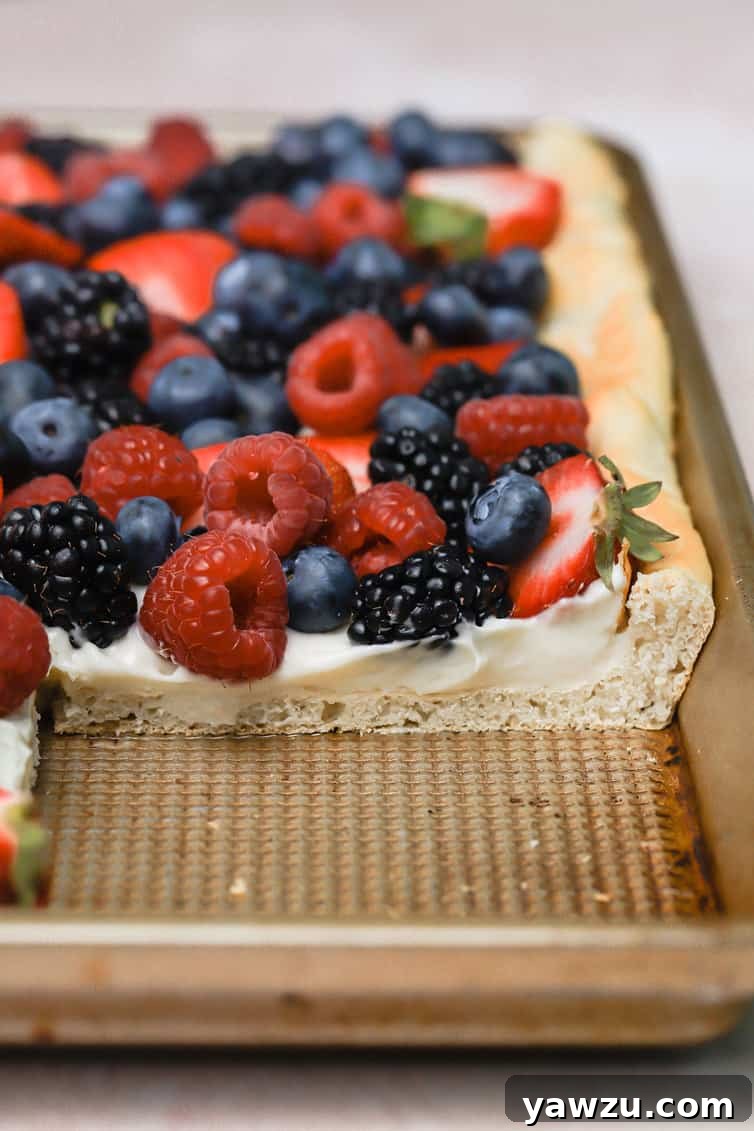 Fruit pizza cut with a large piece removed in the pan.