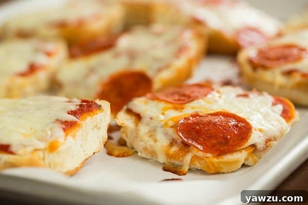 A trio of freshly baked Pizza Burgers arranged on a plate, showcasing their golden-brown edges and bubbling cheese.